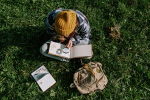 Best Wildlife Biology Degree Programs in the US 4 A person explores flora outdoors using a magnifying glass, surrounded by nature and greenery.