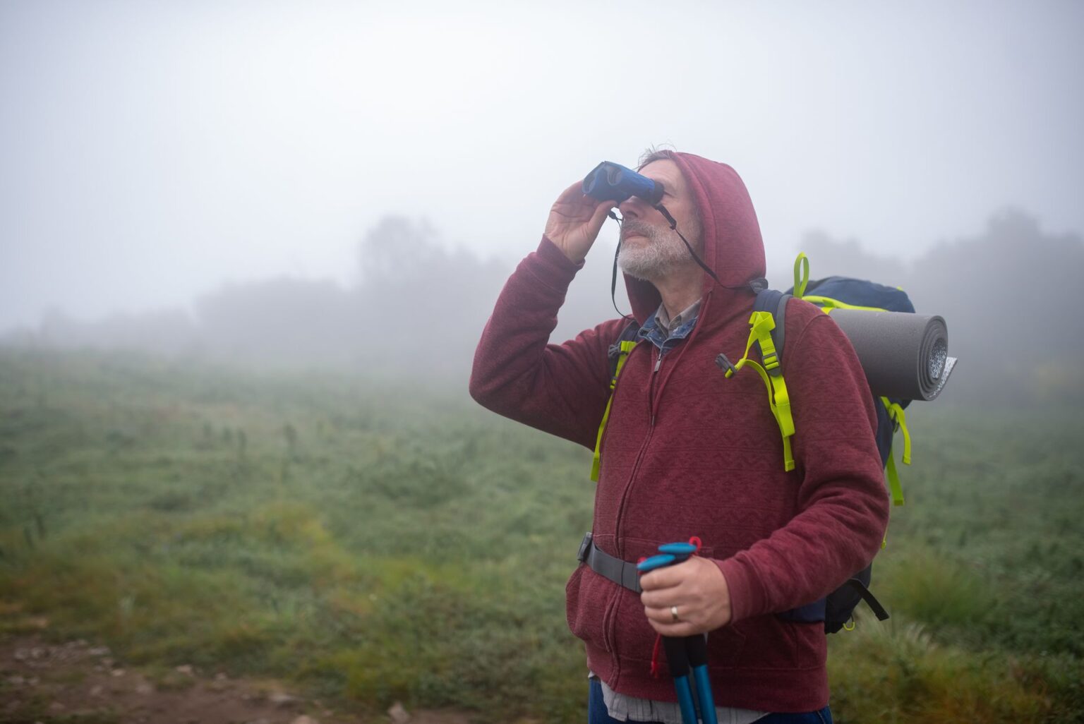 Hiker with binoculars in a foggy landscape