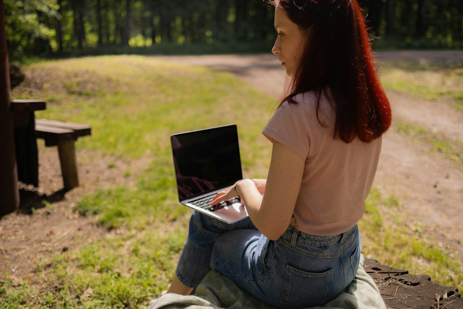 student taking an online wildlife biology course on a laptop in a forest
