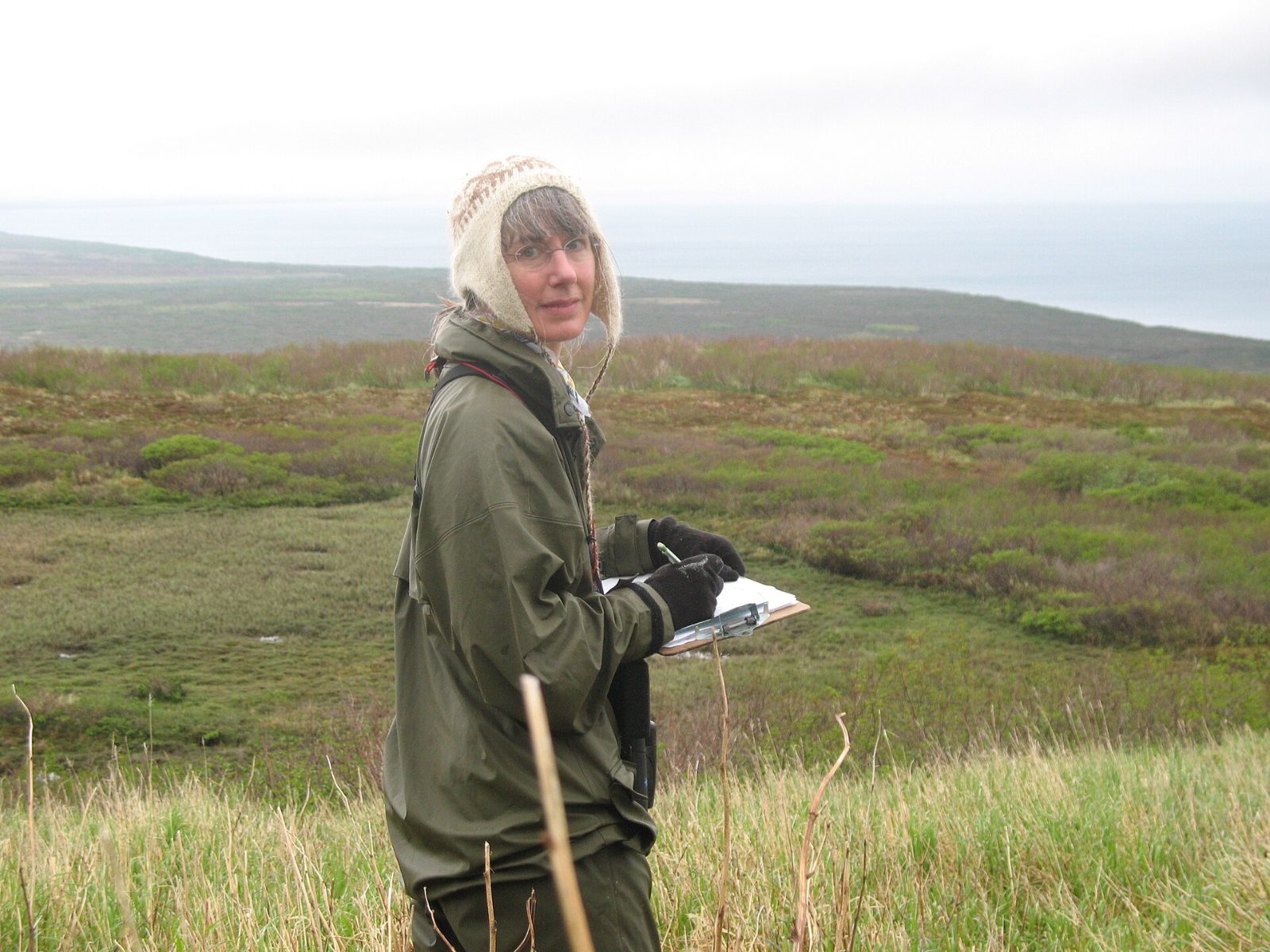 wildlife biologist recording survey data on a clipboard in coastal habitat